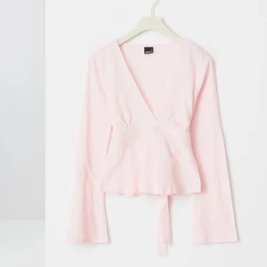 Ljusrosa omlottopp med knyt - Säljer en ljusrosa omlottopp med långa ärmar och knyt i midjan. Toppen har en v-ringad design! 💓💓strl M men passar mig som vanligtvis har Xs/S