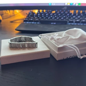 Armband Lacoste - Säljer ett riktigt snyggt silver armband från Lacoste eftersom att jag inte använder den så ofta längre. Just nu är den 18cm lång men fås med en länk till så att den blir nån centimeter längre.