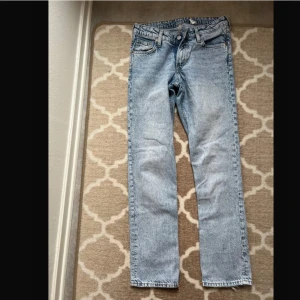 Ljusblå raka jeans från Levis - Ljusblå jeans från Levis med klassisk femficksdesign och raka ben. Jeansen har hög midja och en vintageinspirerad tvätt. Perfekta till vardags för en avslappnad och tidlös look.