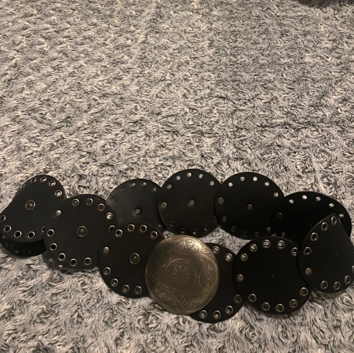 Svart bälte med stora runda nitar och silverfärgat spänne