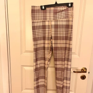 Beige och bruna rutiga leggings från Aim'n - Supersnygga leggings från Aim'n i beige och brunt rutigt mönster. De har en tight passform och hög midja, perfekta för att sticka ut med din outfit. Mjukt och stretchigt material som känns skönt mot huden.