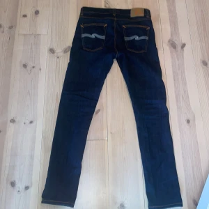 Mörkblå jeans från Nudie Jeans - Snygga mörkblå jeans från Nudie Jeans. Modell är Lean Dean. Säljer dem på grund av att dem är för små. Nästan helt nya bara använda 2-3 gånger, skick 10/10 storlek 30/32. Pris kan diskuteras. Midja 83cm längd 103 cm
