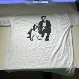 Vit t-shirt med tryck från Fruit of the Loom - Vit t-shirt från Fruit of the Loom med svart tryck av Ulf Kristerson Klassisk passform och rund halsringning. Perfekt för dig som gillar unika motiv och Grisch stil. Skriv om ni har några frågor