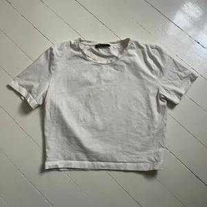 Vit t-shirt från Zara - En basic vit croppad t-shirt från Zara med rund halsringning och korta ärmar. Perfekt till jeans eller kjol för en enkel och stilren look. Skriv för fler bilder💞