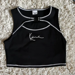Karl Kani crop top - En crop top från Karl Kani! Använd bara en gång! Väldigt stressigt tyg! Perfekt för sommarens konserter, utekvällar och festivaler! Croptoppen har en cutout vid brösten och ett fungerande spänne som detalj! Nypris ca 350 kr
