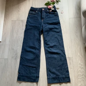 Mörkblå lågmidjade wide jeans med raka ben - Snygga mörkblå jeans med raka, vida ben och klassiska kontrastsömmar. Byxorna har fem fickor och låg midja. Tillverkade i kraftigt denimtyg som ger en cool och tidlös look.