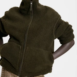 grön teddyjacka hm - Mysig mörkgrön teddyjacka med hög krage och hel dragkedja framtill. Jackan har stora fickor och en avslappnad passform, perfekt för kyliga dagar. Materialet är fluffigt och ger en cool, avslappnad vibe. Från HM helt slutsåld.