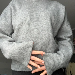 Grå stickad tröja med rund hals - Mysig grå stickad tröja med rund halsringning och långa ärmar. 