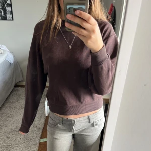 Brun sweatshirt från Gina tricot - Mysig brun sweatshirt från Gina Tricot i storlek XXS. Tröjan har en klassisk rund halsringning, ribbade muddar och är tillverkad i mjuk bomullsmix. Perfekt för chill dagar och enkel att matcha med jeans eller mjukisbyxor.