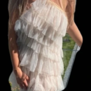 NA-KD volangklänning  - Superfin kort volangklänning i champagnefärg med  flera lager av tunna volanger. Klänningen har glittriga detaljer i nyskick. 