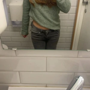 Grön stickad tröja från Vero Moda - Mysig grön stickad tröja från Vero Moda i storlek S. Tröjan har en klassisk rund halsringning, långa ärmar och ribbade muddar. Perfekt för lager-på-lager och chill dagar. Enkel och stilren design som funkar till det mesta.