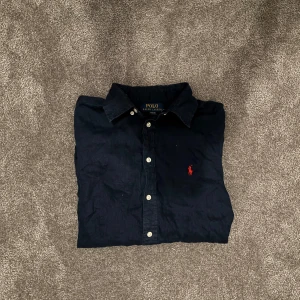Mörkblå Ralph Lauren skjorta - Mörkblå Ralph Lauren skjorta i storlek 14-16| nypris 1200 mitt pris: 599| nästan helt ny| skriv vid minsta fråga!