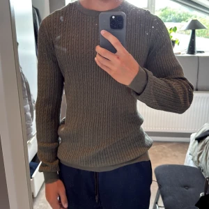 Olivgrön ribbstickad tröja - Säljer en olivgrön ribbstickad tröja med rund halsringning och långa ärmar. Tröjan har en tight passform och är perfekt för kyligare dagar. Stilren och enkel design som passar till det mesta.