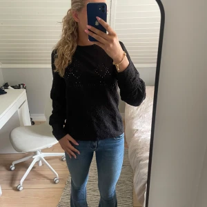 Svart blus med spetsdetaljer - Säljer en svart blus med fina spetsdetaljer och diskret mönster. Blusen har långärmade ärmar och en något lös passform, perfekt till jeans eller kjol.