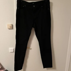 Svarta skinny jeans från xlint - Svarta skinny jeans från xlint med klassisk femficksdesign och knappgylf. Snygg passform som sitter tight hela vägen ner. Perfekta till sneakers eller boots och funkar året runt.Katt finns i hemmet 