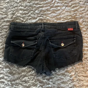 Svarta jeansshorts från Angelic - Jätte snygga svarta jeansshorts från Angelic. Jag köpte de här på plick men säljer dem eftersom att dem inte passar mig. Shortsen har en klassisk femficksmodell, dragkedja och knapp framtill.