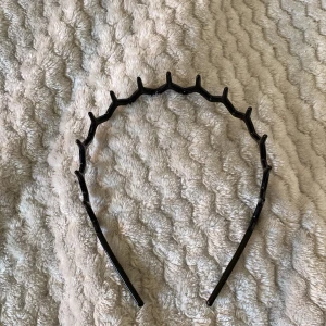 Svart taggigt diadem i plast - Säljer ett svart diadem i plast med taggig, vågig design som håller håret på plats. 🩷