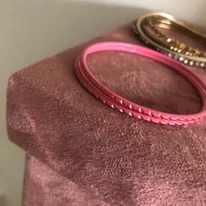 Rosa armband med räfflad kant - Snyggt rosa armband i metall med räfflad kant som ger en cool och unik look. Perfekt accessoar för att lyfta din outfit med lite färg och edge.