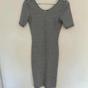Randig svartvit ribbad klänning - Säljer en tight svartvit randig klänning med kort ärm och rundad halsringning både fram och bak. Klänningen är ribbad och har en kroppsnära passform som framhäver siluetten. Perfekt för dig som gillar en enkel men stilren look.