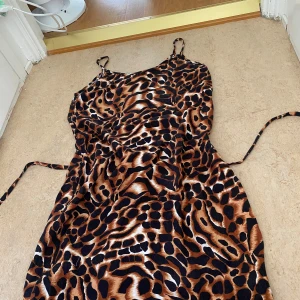 Leopard klänning  - Snygg leopardmönstrad klänning med smala axelband och knytband i midjan. Klänningen har en figurnära passform. 