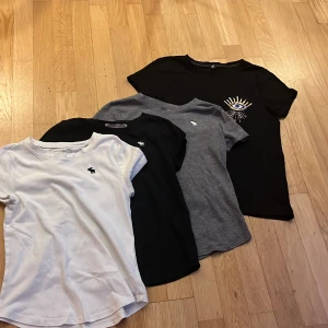 T-shirtpaket Abercrombie & Kids Only - Fyra snygga t-shirts i bomull från Abercrombie Kids och Kids Only. En vit, en grå och en svart med liten logga på bröstet samt en svart med coolt broderat öga och strålar. Alla har rund hals och kort ärm, perfekt till jeans eller shorts.