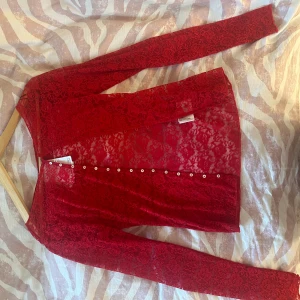 Röd spetsblus från Monki med knappar - Säljer en röd långärmad spetsblus från Monki. Den ör super söt men storleken stämde tyvärr inte. Den är helt ny och har kappen kvar!