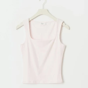 Ljusrosa linnetopp från Gina Tricot - Supersöt ljusrosa linnetopp från Gina Tricot med fyrkantig ringning och breda axelband. Toppen är i mjuk bomull och har en slim passform som sitter snyggt. Toppen är använd 1 gång och säljs pågrundav att den är för liten