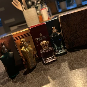 Jean Paul Gaultier Miniatyr Parfymset - Säljer ett miniatyrset med fyra ikoniska parfymer från Jean Paul Gaultier. Flakongerna har coola kroppsinspirerade former i blått, svart, guld och klart glas med gulddetaljer. Perfekt för dig som vill testa flera dofter eller ha snygga samlarflaskor.