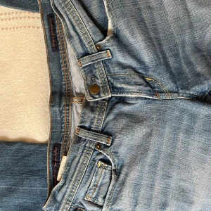 Blå lågmidjade jeans med brodyr - Snygga blå jeans med raka ben och cool broderad detalj i rosa på bakfickorna. Klassisk femficksmodell med gylf och knapp, samt kontrastsömmar. Perfekta för dig som gillar en avslappnad men ändå stilren look.