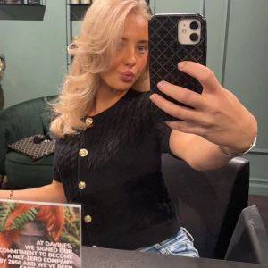 Svart stickad kofta med guldknappar - Kort svart stickad kofta med snygga guldknappar framtill. Koftan har korta ärmar och ett diskret kabelstickat mönster. Passar perfekt nu till sena sommarkvällar eller hösten 💓💓 storlek m men passar allt från xs-m beroende på hur man vill att den ska sitta