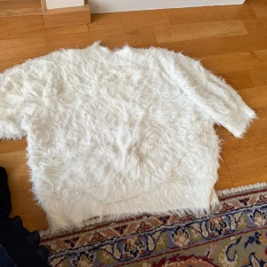 Vit fluffig pälsimitationströja - Supermjuk och fluffig vit tröja med pälsimitation. Tröjan har kort ärm och är perfekt för en mysig outfit🩷