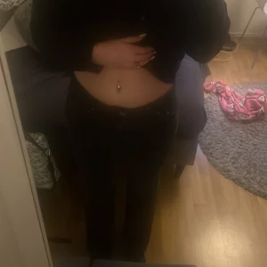 Svarta raka jeans med fickdetaljer - Säljer ett par svarta jeans med raka ben och snygga fickor med knapp bak. perfekt till sneakers eller boots. Jeansen har midwaist och är tillverkade i jeansmaterial. Snygga och enkla att matcha med din favorittröja.