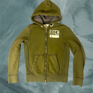 Olivgrön hoodie från Abercrombie & Fitch - Piss snygg olivgrön hoodie med dragkedja från Abercrombie & Fitch. Med en tjock huva med och en olivgrön färg är den perfekt för dig som vill ha ett bekvämt och snyggt plagg i din garderob . Kan tänka mig gå ner i pris vid snabb affär. Modellen är 184, väger 74 ish. Ha det gött!//Gidlöfs
