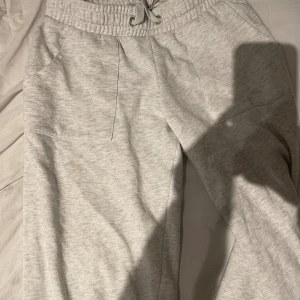 Ljusgrå mjukisbyxor med snörning - Ljusgrå mjukisbyxor från 157 med elastisk midja och snörning. Byxorna har två sidofickor fram och två bakfickor. Perfekta för chill dagar eller när du vill vara extra bekväm. Tillverkade i mjukt bomullsmaterial.