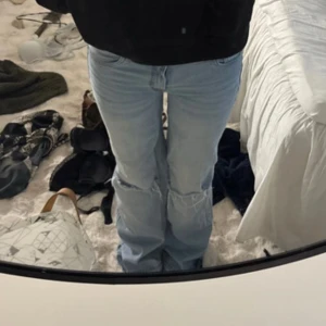 Ljusblå ripped jeans med wide fit - Säljer ett par ljusblå jeans med bred passform och slitna detaljer vid knäna. Jeansen har klassisk femficksdesign och är tillverkade i jeansmaterial. Perfekta för dig som gillar en avslappnad och trendig stil.