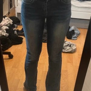 Blå bootcut jeans med broderade fickor - Säljer ett par blå bootcut jeans med snygga broderade detaljer på bakfickorna och klassiska kontrastsömmar. Jeansen har normal passform och är tillverkade i jeansmaterial. Perfekta för dig som gillar en lite retro vibe och vill ha något som sticker ut.