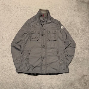 Grå vindjacka från Moncler - Snygg och ertertraktad Moncler jacka i en skön grå färg. Perfekt till nu till hösten och vintern! Storleken är 3 vilket motsvarar M. Se bilder för skick! 
