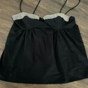 Svart glittrig tubtopp från Zara - Supersnygg svart tubtopp från Zara med glittriga silverpaljetter längs överkanten. Toppen har tunna axelband och en lätt utsvängd form som ger en cool och trendig vibe. Perfekt för att sticka ut med extra bling! Materialet känns mjukt och lätt.
