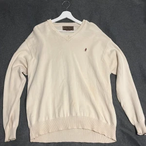 Stickad tröja Marlboro Classics - Säljer en beige stickad tröja från Marlboro Classics i storlek XL. Tröjan har v-ringad hals, ribbade muddar och en liten broderad cowboy-figur på bröstet. Perfekt för dig som gillar klassisk och enkel stil med en touch av western. Pris kan såklart diskuteras 