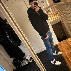 Moncler cardigan - Svart cardigan jacka från Moncler med stickad kropp och quiltad huva. Jackan har dragkedja framtill, två sidofickor med dragkedja och Moncler-logga på ärmen. Perfekt för dig som gillar stilren och sportig look. 