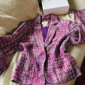 Rutig kavaj från Chadwick's i lila och rosa - Säljer en snygg rutig kavaj från Chadwick's i lila, rosa och vita toner. Kavajen har två framfickor, klassisk krage och knäppning med två knappar. Materialet är grovt vävt och fodret är lila. Perfekt för dig som gillar färg och struktur.