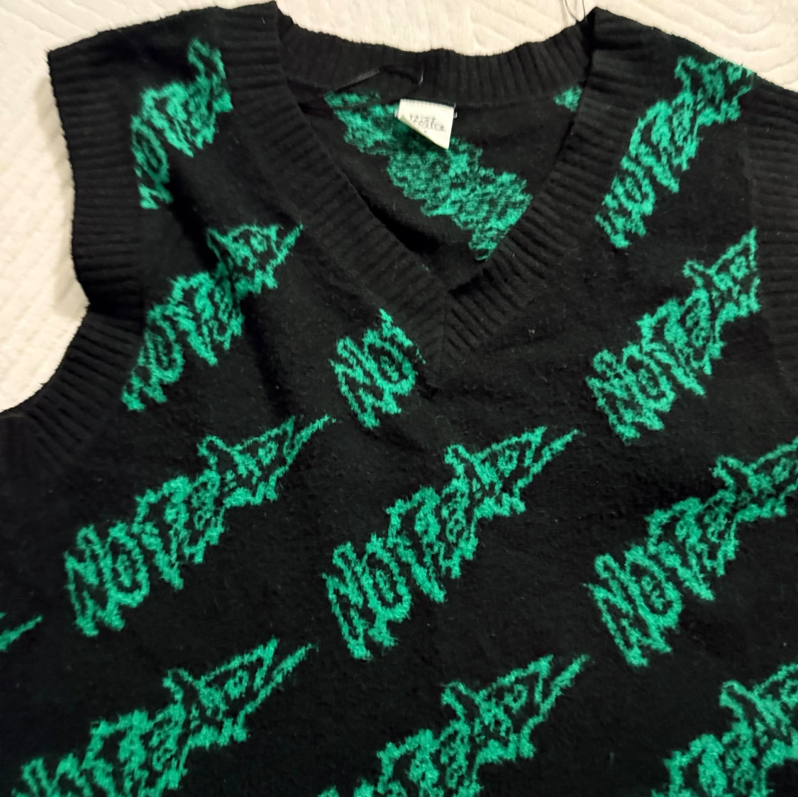 Svart stickad väst med grön text - 1