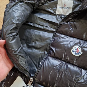 Moncler Vest Glossy - Svart Moncler vest, som sitter fint på vintern, bra kvalite men lite använd. Kvalite: 8.5/10 (Prislappar inte inkluderade)                                                             Jag är öppen att prishandla för rimligt pris.