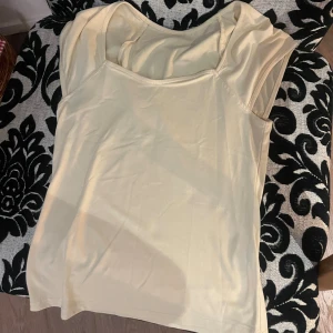 Ljusgul ärmlös linnetopp - Snygg ljusgul linnetopp med enkel och stilren design. Toppen är ärmlös och har en mjuk rundad halsringning. Perfekt för varma dagar och enkel att matcha med olika outfits. Materialet känns lätt och bekvämt mot huden.