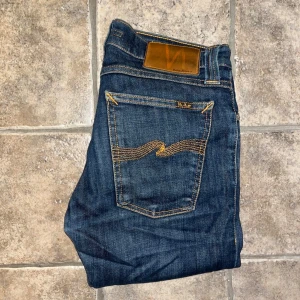 Nudie Jeans  - Mörkblå skinny jeans från Nudie Jeans, modell Tight Long John. Snygga kontrastsömmar och klassisk femficksdesign. Stretchigt denimmaterial i bomull för skön passform. Bakfickorna har Nudie Jeans signaturbroderi i gult. Midja 36cm, längd 101cm.  Ifall det inte finns någon bild i annonsen där jag bär plaggen jag säljer så är det för att jag ej kan ha storleken heller passformen, så kolla måtten för storlek och googla på modellnamnet för passform 😉 s4