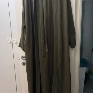 Khakigrön abaya - Superfin abaya som går att använda på flera olika sätt! Kommer med underklänning, kimono och skärp. Använt enstaka gånger nyskick!