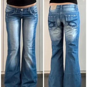 Blå bootcut jeans med broderade fickor - Snygga blå bootcut jeans,  ljusa partier framtill. Bakfickorna har coola broderade detaljer och jeansen har låg midja. Perfekta för dig som gillar en retro vibe och vill sticka ut lite extra.