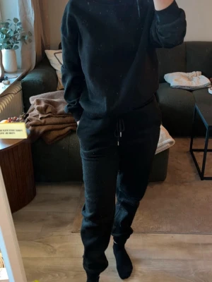 Svarta mjukisbyxor med snörning, S - Svarta mjukisbyxor i storlek S, tillverkade av 95% polyester och 5% spandex. Byxorna har elastisk midja med snörning för skön passform och är perfekta för chill dagar hemma. Materialet är mjukt och stretchigt, vilket gör dem riktigt bekväma.