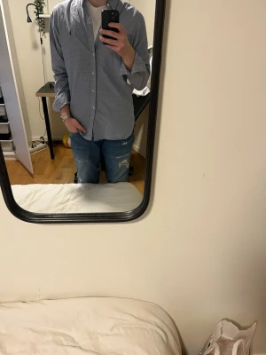 Blårutig skjorta från Ralph Lauren - Säljer en blårutig skjorta från Ralph Lauren med klassisk krage och knappar framtill. Skjortan har lång ärm och en diskret logga på bröstet. Perfekt för dig som gillar stilrena och tidlösa plagg. Passar dig som vill ha en normal passform.