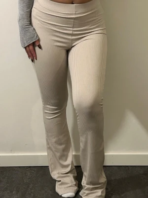 Beige ribbade bootcut byxor - Säljer ett par beige ribbade byxor med bootcut-snitt och hög midja. Byxorna är stretchiga och har en mjuk känsla, perfekta för en chill och snygg look. Passar även mig som är Strl S. 